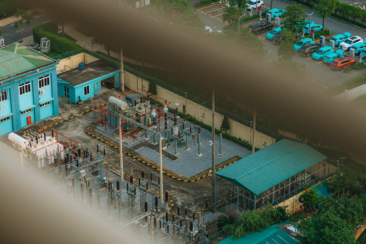 An overhead view of a city electrical substation with surrounding infrastructure.